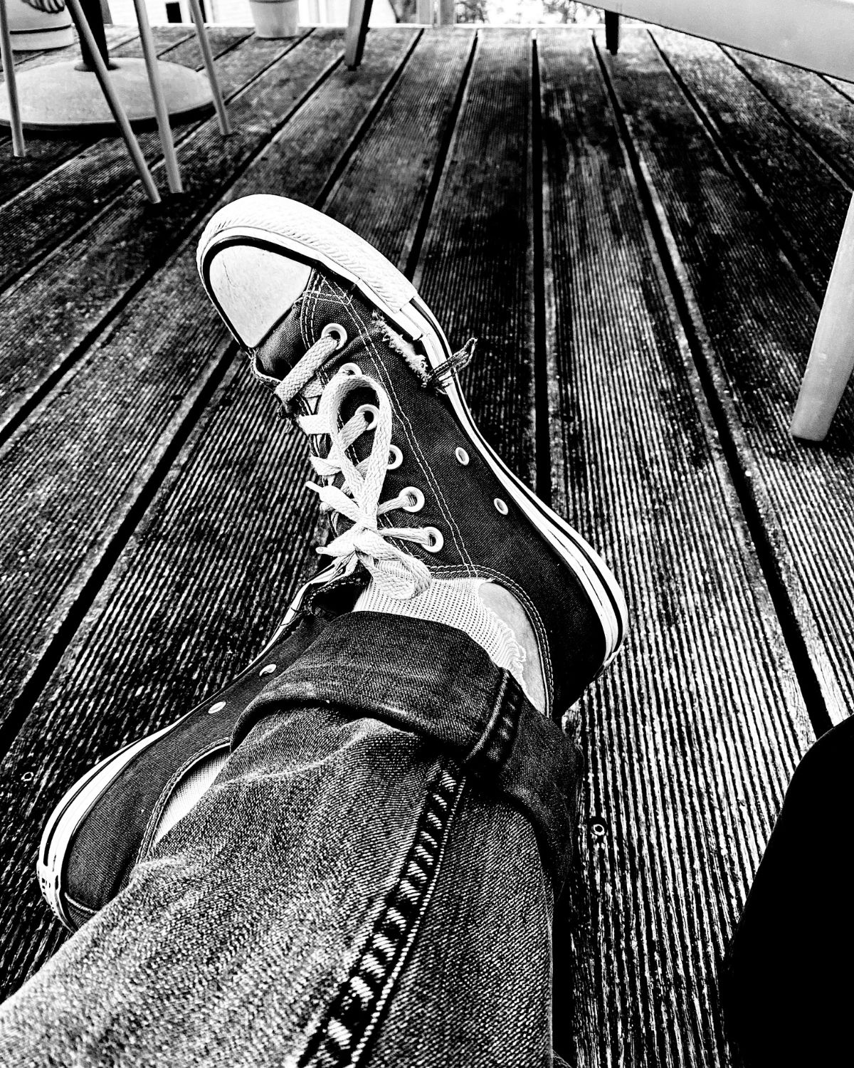Sneakers and crossed legs on a wooden terrace